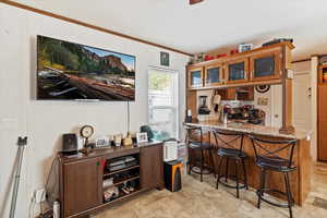 Bar area with light stone counters, crown molding, stainless steel gas range oven, glass insert cabinets, and brown cabinets