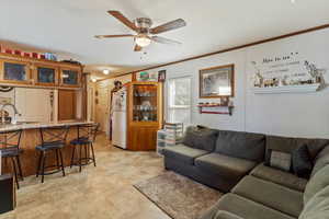 Living area with ornamental molding and a ceiling fan