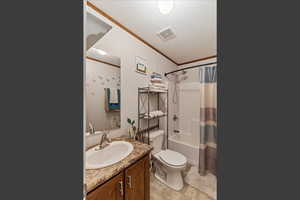 Full bath featuring crown molding, shower / bath combination with curtain, vanity, and a textured ceiling