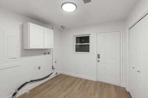 Laundry room with washer hookup, light wood-style floors, hookup for a gas dryer, electric panel, and cabinet space