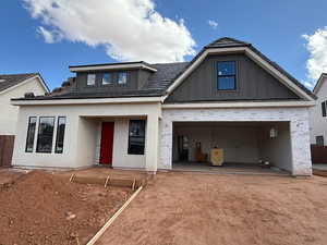 View of front of house featuring a garage, board and batten siding, brick siding, driveway, and covered porch