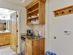 Kitchen featuring dark stone counters, open shelves, and decorative backsplash