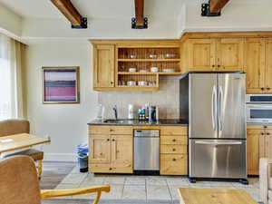 Kitchen with appliances with stainless steel finishes, beam ceiling, decorative backsplash, open shelves, and light tile patterned floors