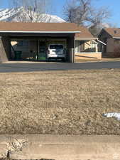 View of property exterior with roof with shingles, an attached carport, a lawn, and a porch