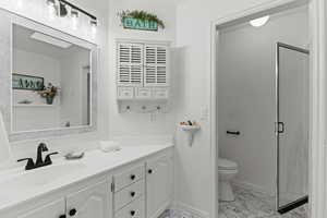 Full bath with vanity, a stall shower, and light marble finish floors