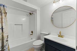 Bathroom featuring shower / bath combination with curtain, vanity, and a textured ceiling