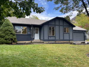 View of front of home with roof with shingles, a front lawn, stucco siding, and an attached garage