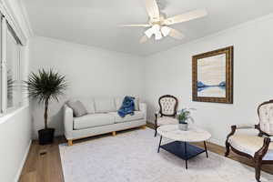 Living area featuring ornamental molding, wood finished floors, and ceiling fan