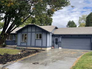 View of front facade featuring roof with shingles, driveway, brick siding, and stucco siding