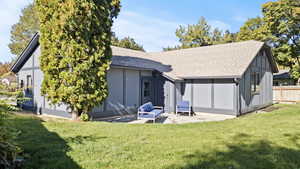 Rear view of property featuring roof with shingles, a patio, and board and batten siding