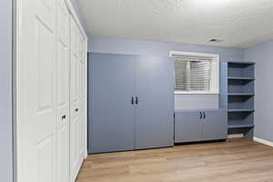 Unfurnished bedroom with a closet, light wood-style floors, and a textured ceiling