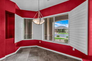 Unfurnished dining area with baseboards and dark stone finish floors