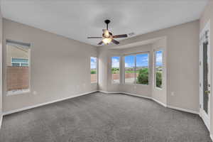 Carpeted empty room featuring ceiling fan and baseboards