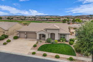 Mediterranean / spanish-style home featuring stone siding, a front lawn, stucco siding, an attached garage, and driveway