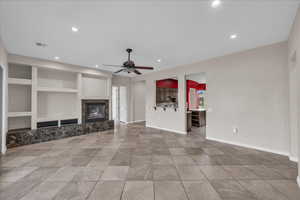 Unfurnished living room featuring built in features, a premium fireplace, recessed lighting, and a ceiling fan
