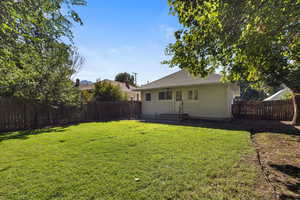 Back of property with a fenced backyard, a shingled roof, and a patio area