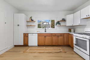 Kitchen featuring open shelves, white appliances, light wood-style flooring, brown cabinets, and white cabinets