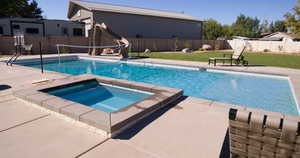 View of pool featuring a patio area, a fenced backyard, a water slide, and a pool with connected hot tub