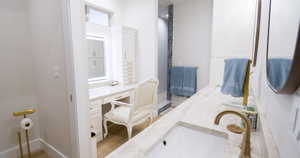 Full bath with double vanity and light wood-style flooring