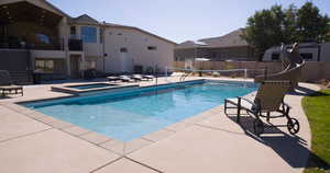 View of swimming pool with a patio, a balcony, a pool with connected hot tub, and a residential view