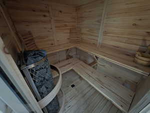 Relaxing sauna / steam room with wooden walls, hardwood / wood-style flooring, and wooden ceiling