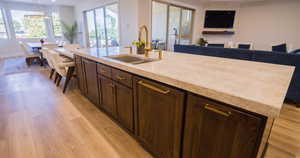 Kitchen with dark brown cabinets, light wood-style flooring, open floor plan, a large fireplace, and hanging light fixtures