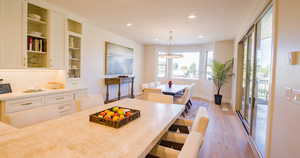 Kitchen featuring light wood finished floors, decorative light fixtures, a breakfast bar, white cabinetry, and recessed lighting
