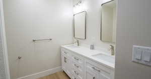 Full bath with double vanity and light wood-type flooring