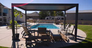 View of pool featuring a patio area, a water slide, a fenced backyard, and a pool with connected hot tub