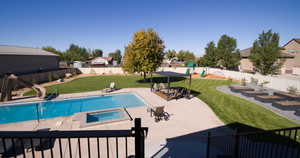 View of swimming pool with a patio area, a fenced backyard, a water slide, an in-ground hot tub, and a vegetable garden
