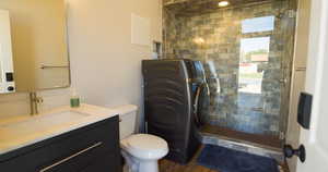 Full bath featuring washer / dryer, a shower stall, vanity, and dark wood-style floors
