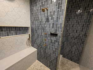 Bathroom featuring tiled shower and tile walls