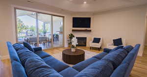 Living area featuring light wood-type flooring, a fireplace, a raised ceiling, and recessed lighting