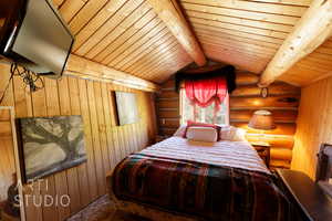 Bedroom with rustic walls and wooden ceiling