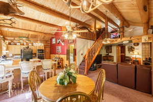 Dining room featuring a chandelier, wood walls, wood ceiling, light colored carpet, and stairway