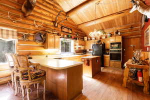 Kitchen with a breakfast bar, light wood finished floors, light countertops, a kitchen island, and wooden ceiling
