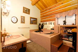 Full bath featuring vanity, a bath, a wood ceiling with exposed beams, and rustic walls