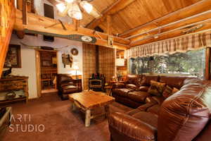 Living area with a wood stove, wood ceiling, carpet floors, and ceiling fan