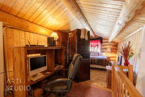 Office area with rustic walls, light colored carpet, wooden ceiling, and wooden walls