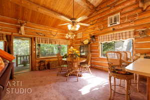 Carpeted dining area with a ceiling fan, a wooden ceiling with exposed beams, and rustic walls