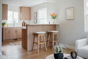 Kitchen with light brown cabinetry, a breakfast bar, tasteful backsplash, and light wood-type flooring