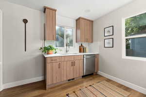 Bar featuring tasteful backsplash, dishwasher, light wood-style flooring, modern cabinets, and light stone counters