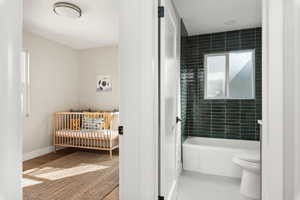 Bathroom with shower / bathtub combination and light wood-style floors