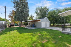 View of yard featuring an outdoor structure, a detached garage, and a patio