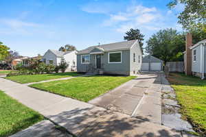 Bungalow-style house with a garage, an outbuilding, and a shingled roof