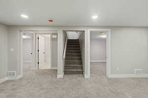 Finished basement with light carpet, stairs, and recessed lighting