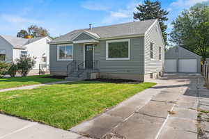 Bungalow-style home with an outdoor structure, a garage, and a front lawn