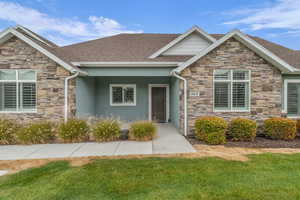 Craftsman inspired home with stone siding, roof with shingles, a front lawn, and covered porch