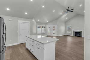 Kitchen with light wood-style floors, freestanding refrigerator, open floor plan, a kitchen island, and a fireplace