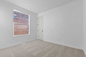 Empty room featuring light colored carpet and baseboards